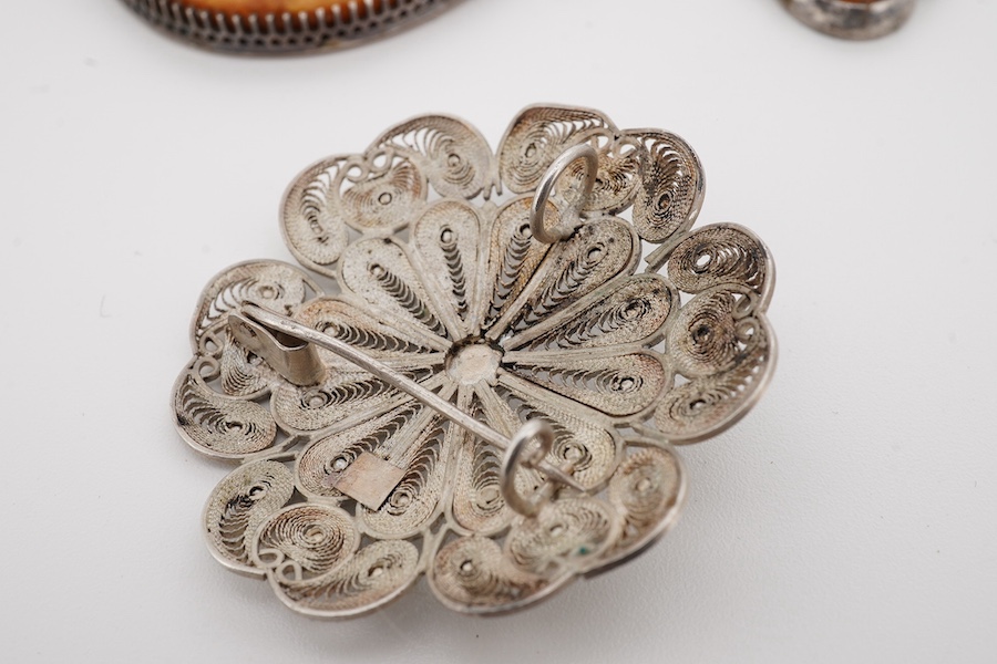 An Indian white metal fringe necklace, 37.5cm, a large antique white metal mounted amber pendant(a.f.), one other later smaller amber pendant and a filigree brooch. Condition - poor to fair